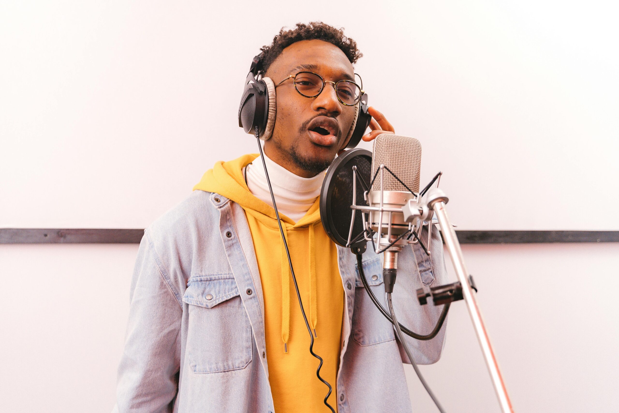 Young African American singer recording music indoors in a studio environment.